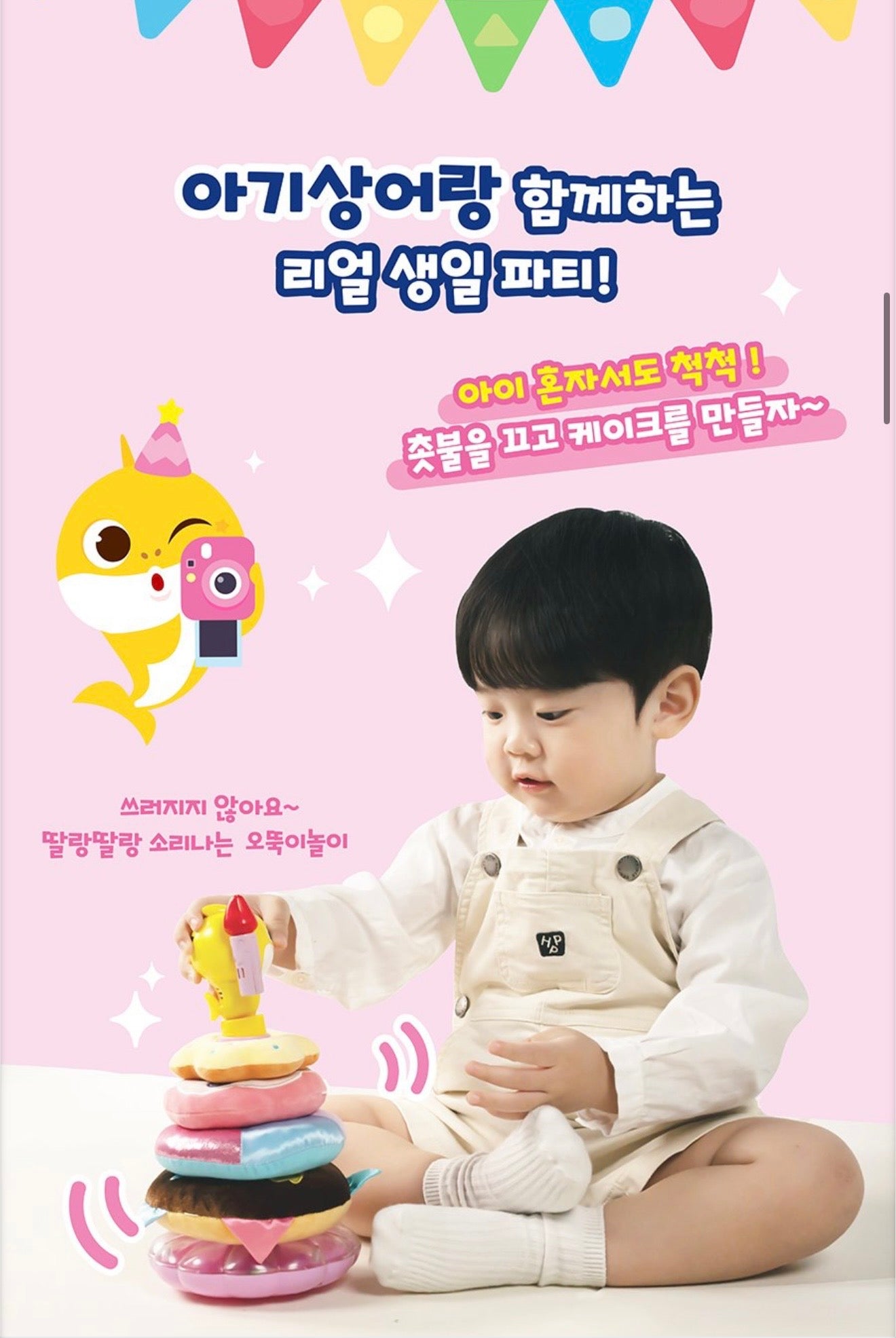 小朋友坐在地上玩 Baby Shark 蛋糕疊疊樂，展示不倒翁底座設計，玩具搖晃時不會倒下並發出清脆鈴聲，適合幼兒獨自玩耍。