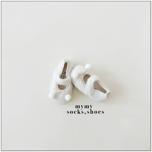  一雙白色的 mymy 品牌嬰兒毛絨學步鞋，鞋頭帶有可愛的毛球裝飾，放置在米白色背景上。