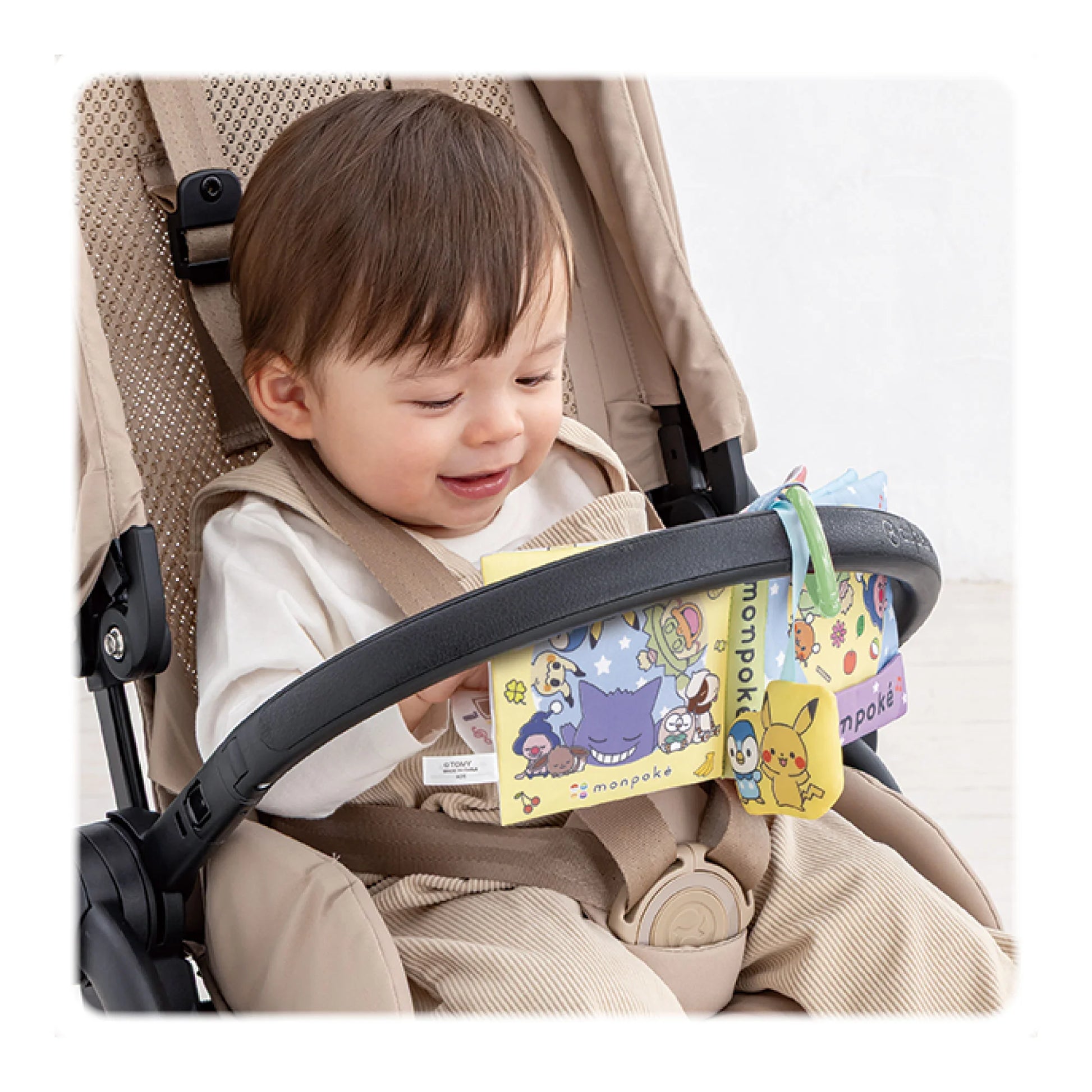 寶寶坐在嬰兒車上閱讀 Monpoké 布書，掛在扶手上方便外出使用