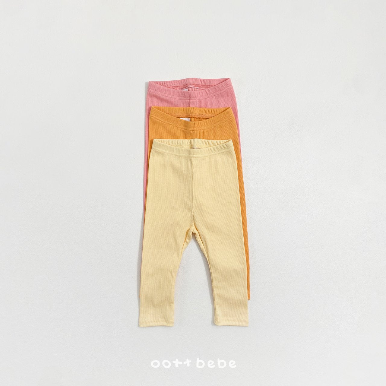 粉紅、橙色、黃色三條嬰兒坑條長褲疊放在一起，展示色彩層次。