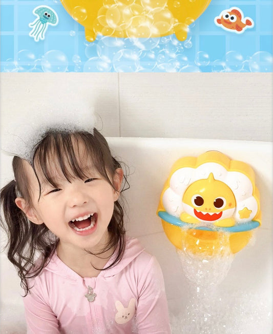 一個可愛的小女孩在浴缸裡開懷大笑，頭上頂著一堆白色泡泡，旁邊牆上掛著正在運作的 Baby Shark 泡泡玩具，展示快樂的洗澡時光。