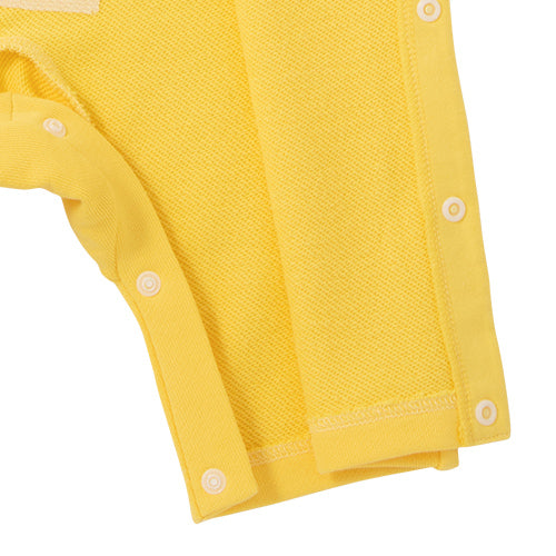 褲腳細節:黃色連身衣褲腳及啪鈕細節特寫，車工精細。