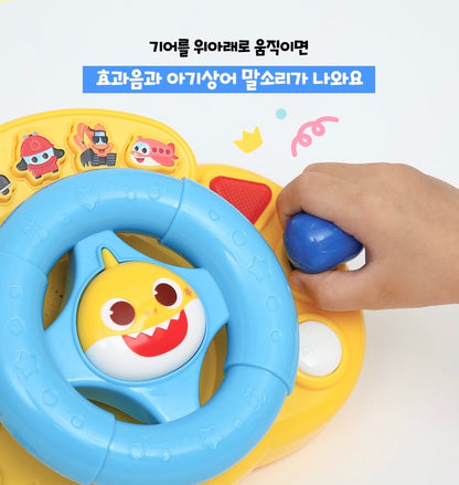 幼兒的小手握住右側藍色的排檔桿進行推動操作。說明文字指出上下移動排檔桿會發出音效與鯊魚寶寶的語音。